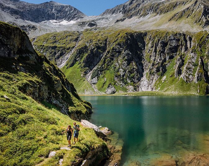 Majestátní alpské vrcholy obklopují smaragdově zelené horské jezero v oblasti Wildkogel-Arena. Turisté si v tomto alpském ráji užívají nedotčenou přírodu a čistý vzduch.