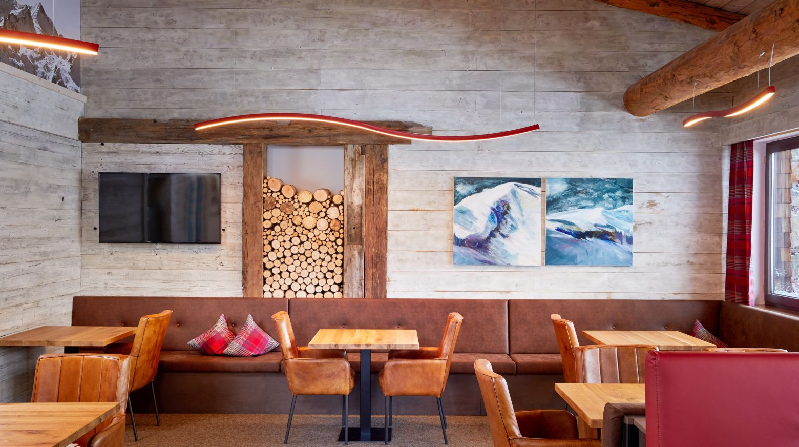 Gezellige café-interieur met houten muren, houten plafonds en moderne kunst aan de muur. Comfortabele zitplaatsen en tafels in warme tinten.
