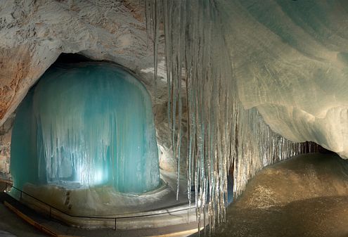 Eine spektakuläre Höhle mit beeindruckenden Eissäulen und glitzernden Eiszapfen an den Wänden, die eine mystische und faszinierende Atmosphäre schaffen.