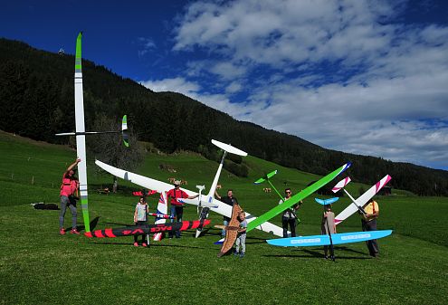 Sonnenaufgang über einem malerischen Tal mit Wäldern und Wiesen. Die Berge umrahmen den Blick, während Sonnenstrahlen die Landschaft sanft erhellen und Nebel sich legt.