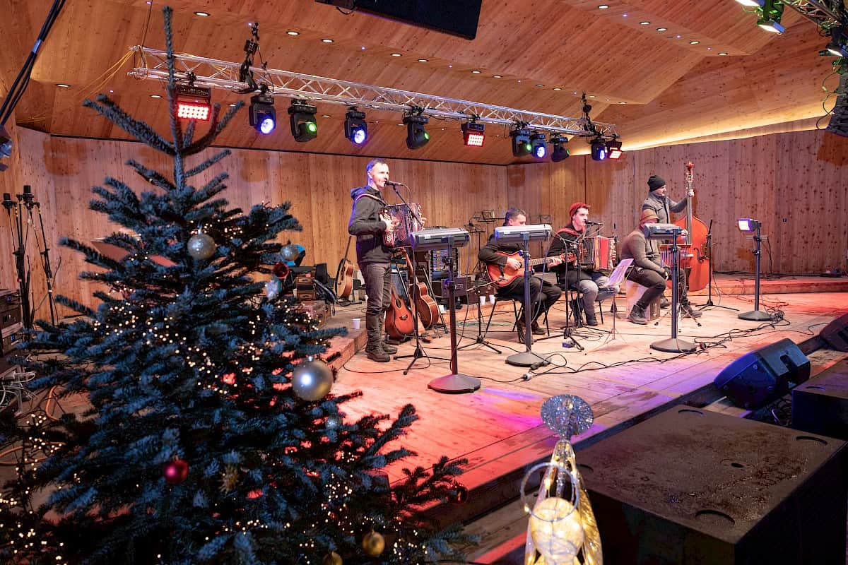 Musicians performing live on a festively decorated stage at "Advent a de Berg" in Bramberg.