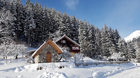 Die Friedburg Kapelle im Winter vor einem verschneiten Wald