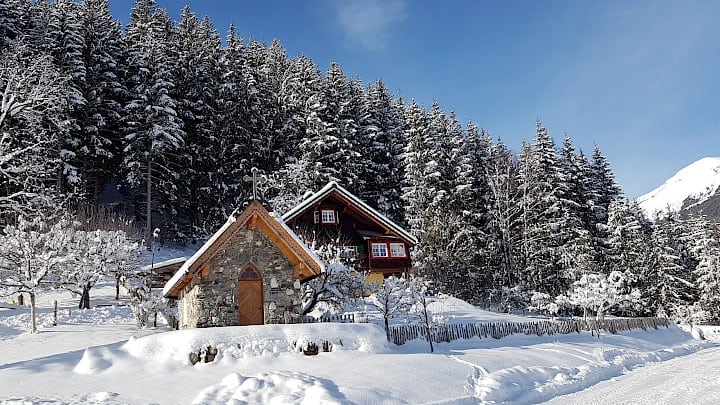 Die Friedburg Kapelle im Winter vor einem verschneiten Wald