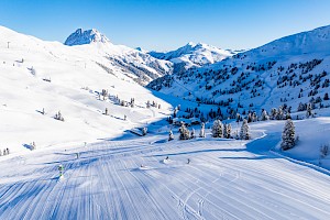 Skifahrer gleiten über frisch präparierte Pisten mit Blick auf den Großen Rettenstein im schneereichen Skigebiet der Wildkogel-Arena Neukirchen & Bramberg.