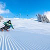 Dynamischer Skifahrer auf perfekt präparierter Piste in der Wildkogel-Arena bei strahlendem Sonnenschein und frischem Pulverschnee.