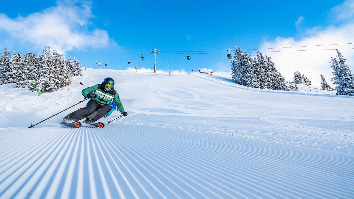 Dynamische skiër op een perfect geprepareerde piste in de Wildkogel Arena bij stralende zon en verse poedersneeuw.