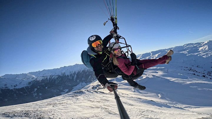 Tandemové paragliding v zimě nad zasněženými horami oblasti Wildkogel Arena – nezapomenutelné dobrodružství s panoramatickým výhledem.