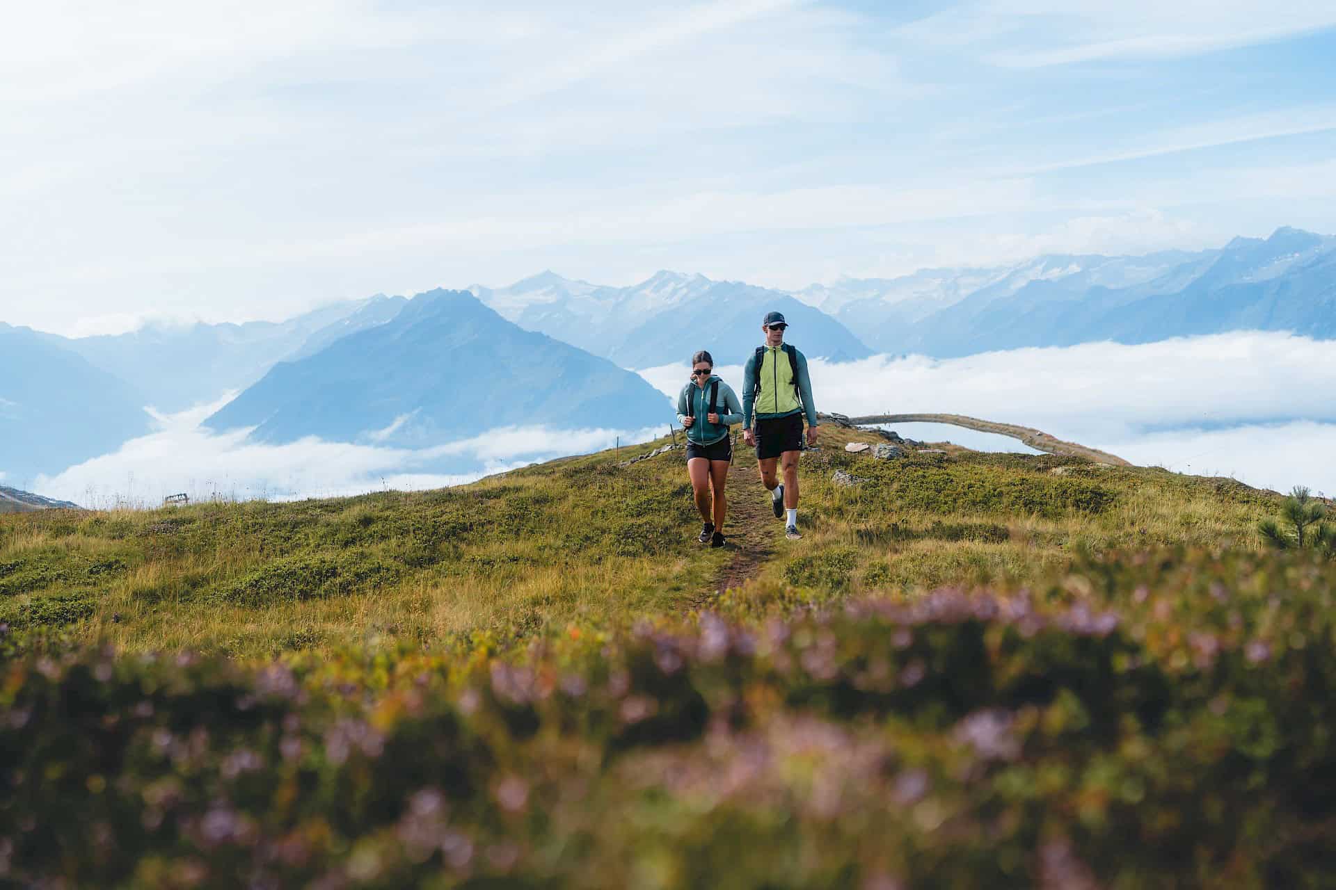 Zwei Wanderer genießen eine Panoramatour im Höhenwandergebiet Wildkogel. Vor ihnen breitet sich ein atemberaubender Blick über das Nebelmeer und die Hohen Tauern aus – Wandern auf über 2.000 Metern inmitten der Salzburger Bergwelt.