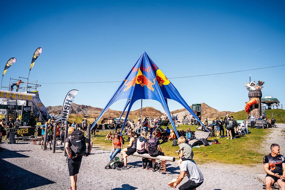 Teilnehmerinnen und Teilnehmer des Predator Race entspannen sich im Zielbereich rund um das Red Bull Zelt an der Bergstation der Wildkogelbahn.