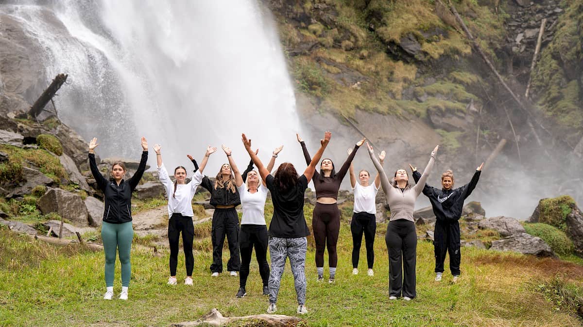 Teilnehmerinnen der Bewegungswoche „Bergzeit – move & soul retreat“ bei einer Achtsamkeitseinheit direkt vor den beeindruckenden Krimmler Wasserfällen.