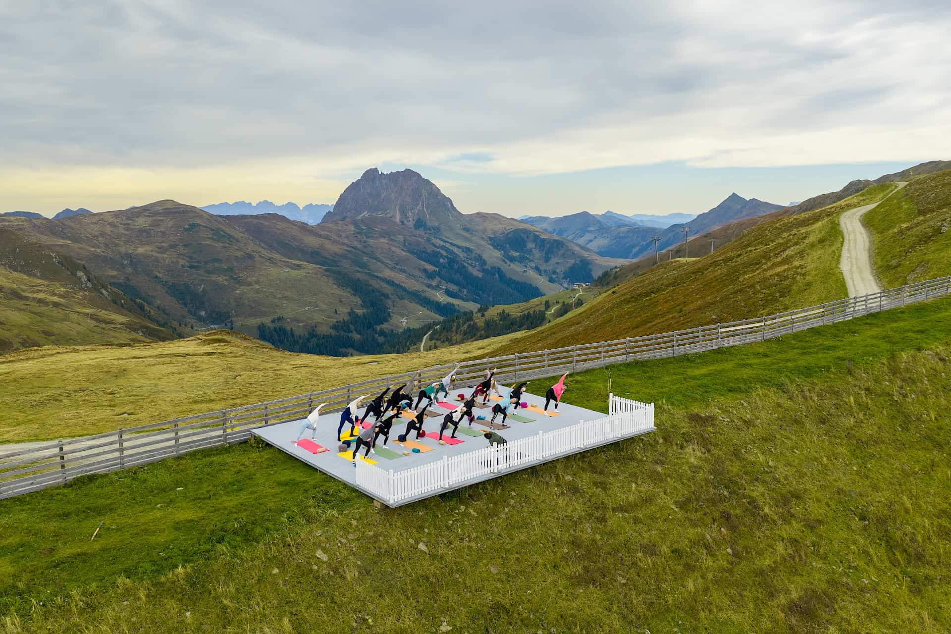 Yoga auf einer frei stehenden Plattform am Wildkogel, eingerahmt von sanften Almwiesen. Im Hintergrund ragt majestätisch der Große Rettenstein in den Himmel.