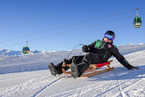 Rodler auf der längsten, beleuchteten Rodelbahn de Welt mit der Smaragdbahn im Hintergrund