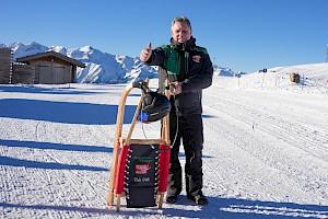 Mann mit Rodel in der Hand im Hintergrund die Wildkogel-Arena
