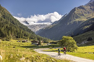Zwei Radfahrer genießen das sonnige Habachtal, unterwegs zur Enzianhütte mit Blick auf Gletscher am Talschluss.