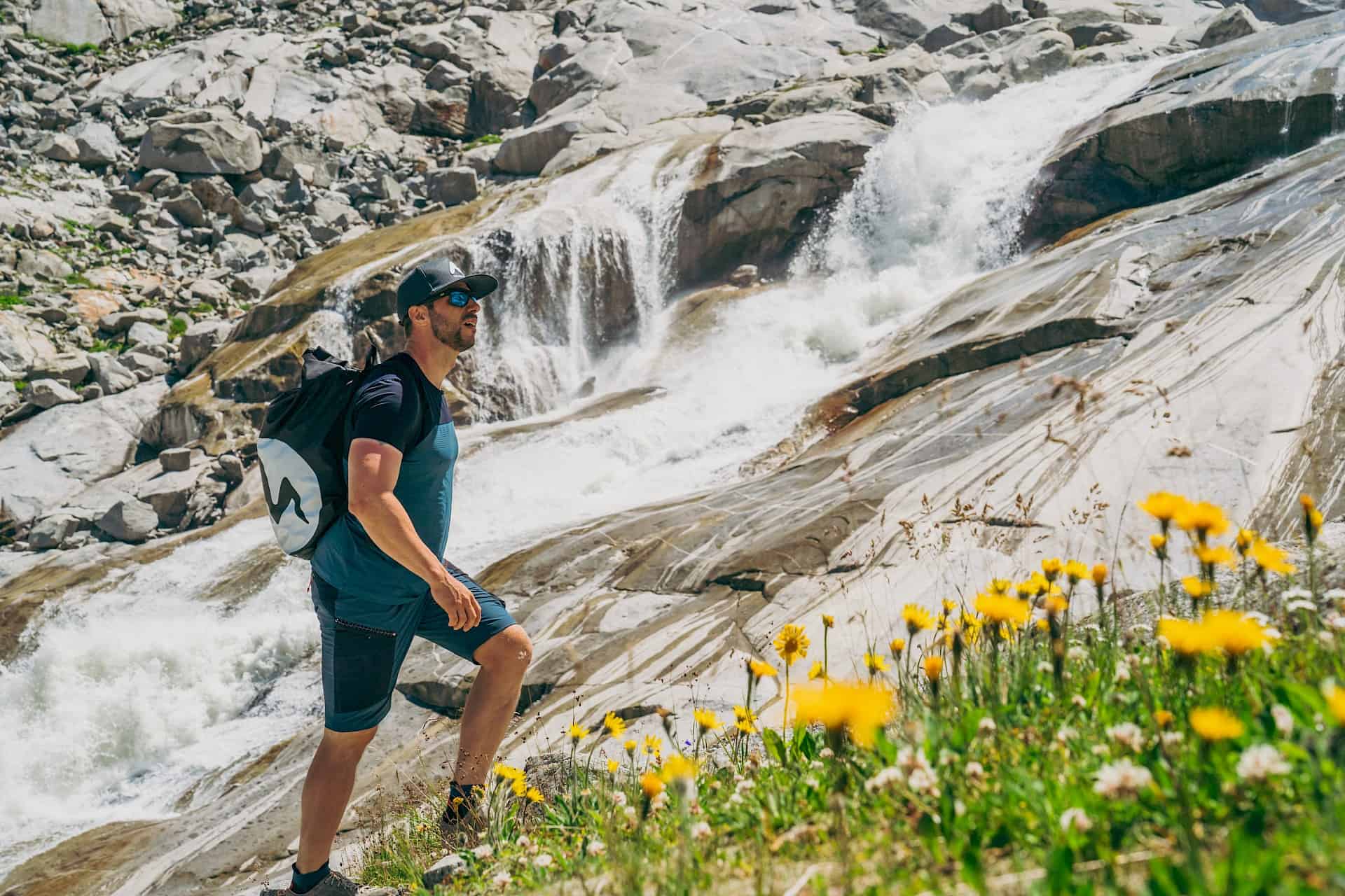 Turista u vodopádu v Národním parku Vysoké Taury – monumentální skály, hučící voda a kvetoucí horské louky.