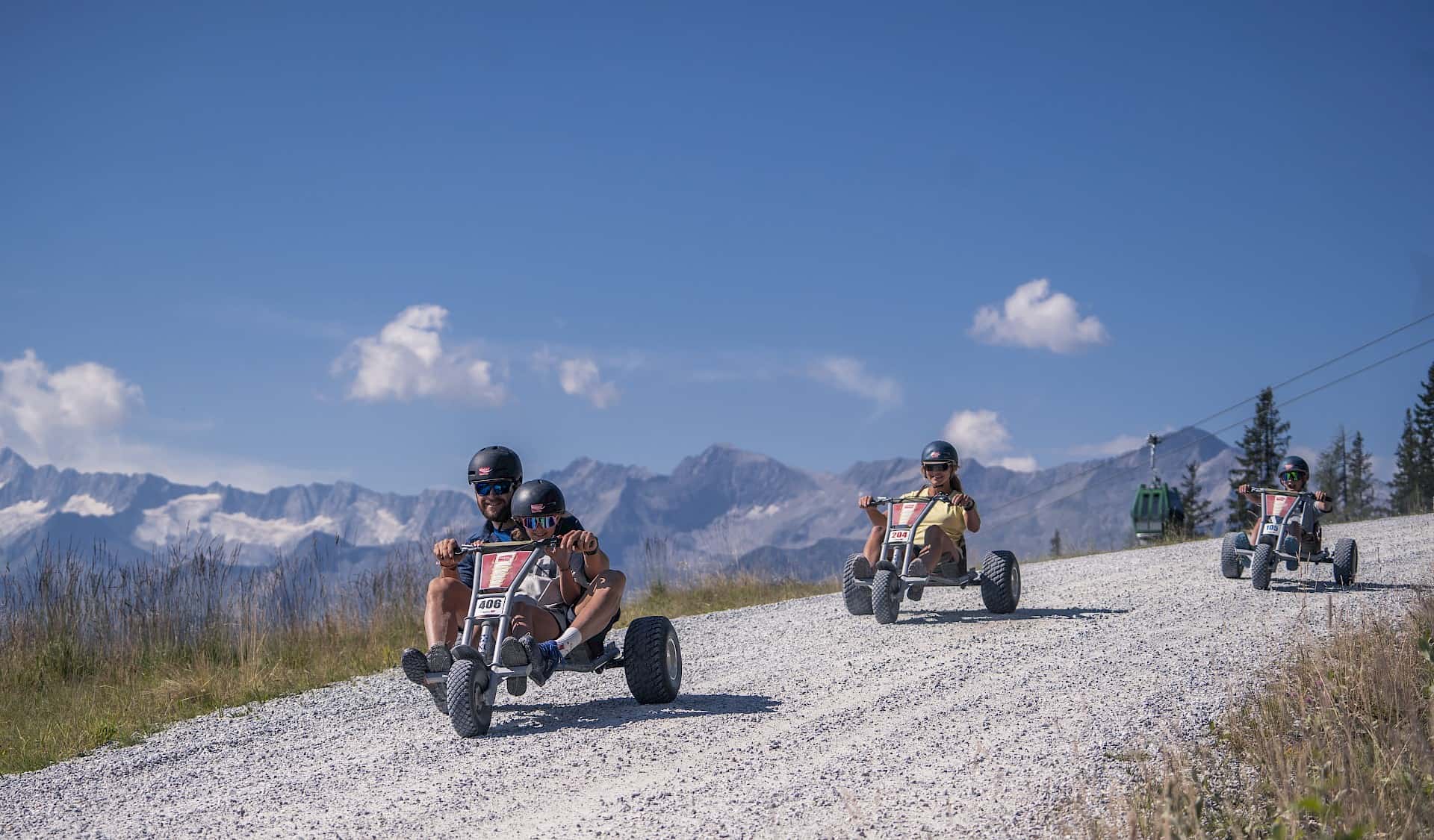 Family riding mountain carts down the 4 km long mountain cart track in the Wildkogel Arena – a thrilling outdoor activity for all ages with panoramic views of the peaks of the Hohe Tauern.