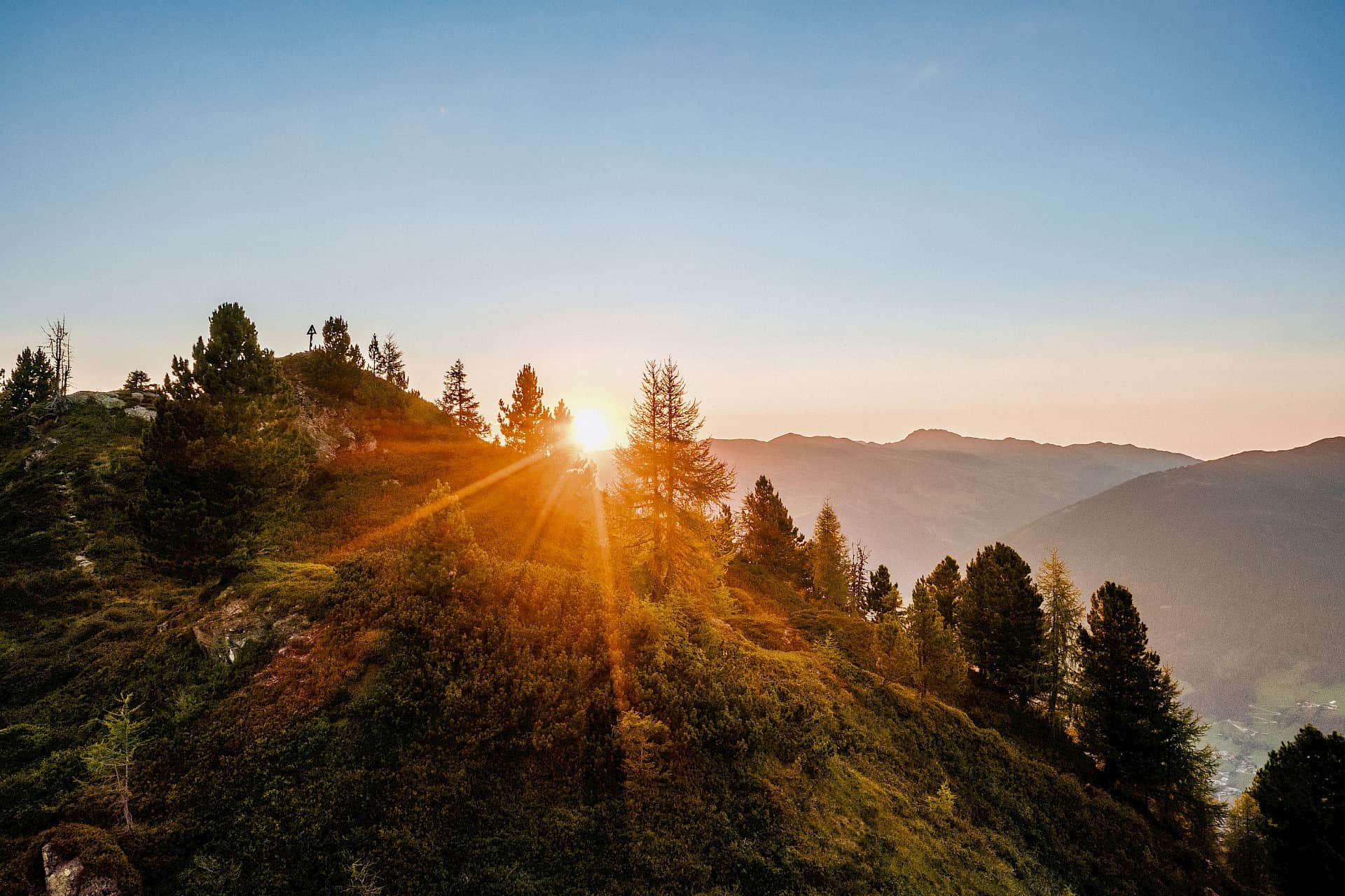 Působivý východ slunce nad horským turistickým územím Wildkogel s výhledem na majestátní Vysoké Taury. První sluneční paprsky zalévají horskou krajinu do zlatého světla – nezapomenutelný přírodní zážitek pro milovníky hor a turistiky.